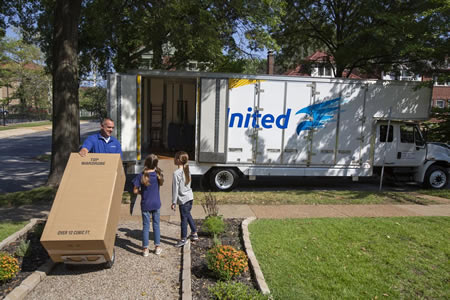 Professional movers carrying a big box into a Gulf Breeze FL home