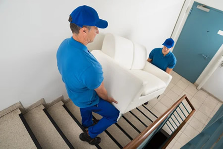 Professional movers carrying a sofa into a Milton, FL home